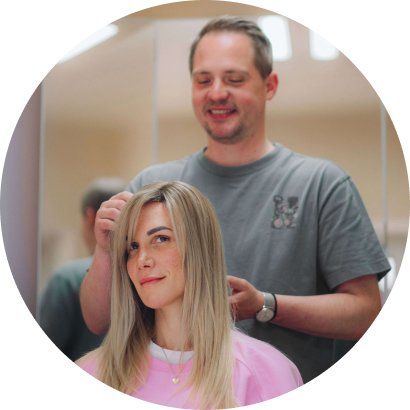 Mann berät sitzende Kundin mit langen blonden Haaren.